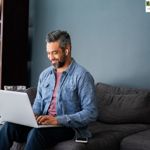 Man working from home on his sofa with a computer, exploring top freelancing platforms for remote work."