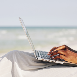 A woman working remotely from the beach on her computer, highlighting the flexibility of remote jobs in 2024."